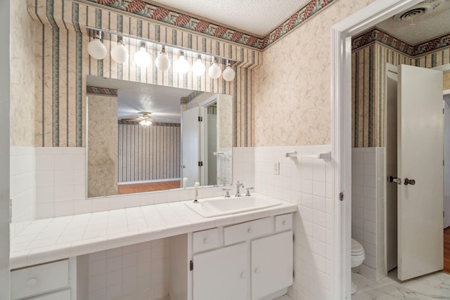 bathroom with vanity, tile walls, toilet, and a textured ceiling