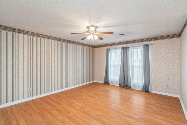 empty room featuring ceiling fan, wood-type flooring, and a textured ceiling