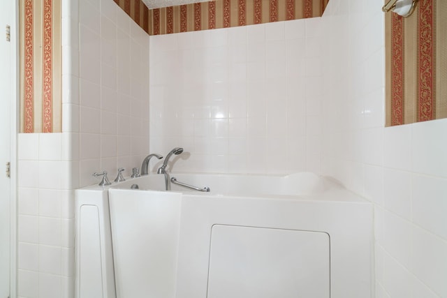 bathroom with tile walls and a tub