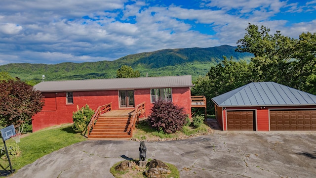 view of front facade with a mountain view, metal roof, an outbuilding, and stairway