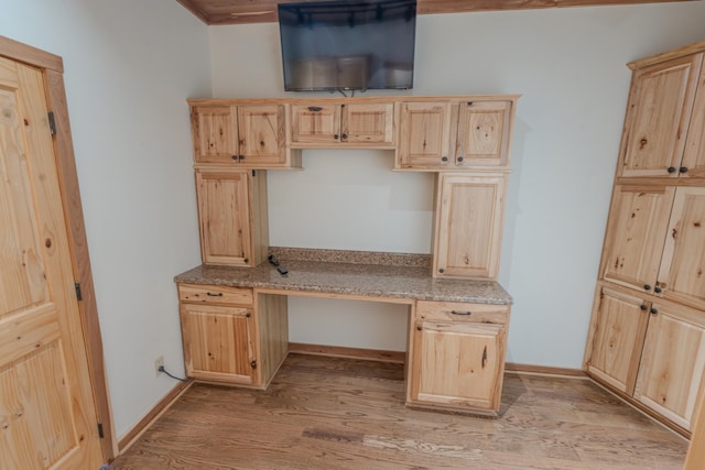 kitchen featuring light brown cabinetry, built in desk, and light wood-type flooring