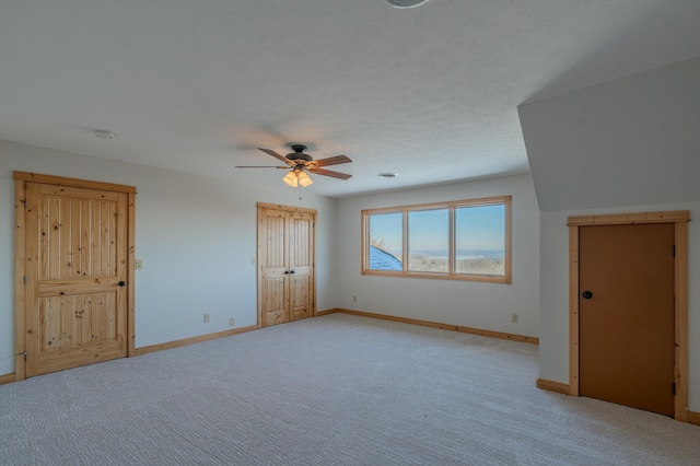 empty room with ceiling fan, light carpet, and a textured ceiling