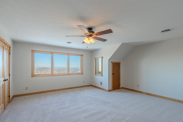 bonus room with light colored carpet, ceiling fan, and baseboards