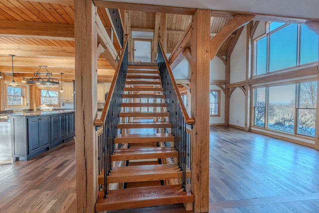 stairs with beam ceiling, hardwood / wood-style floors, and a wealth of natural light