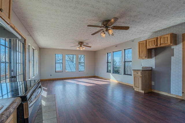 unfurnished living room featuring ceiling fan, dark hardwood / wood-style flooring, and a textured ceiling