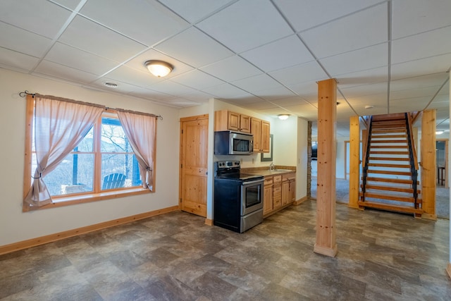 kitchen with stainless steel appliances, baseboards, a drop ceiling, and a sink
