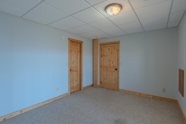 carpeted empty room with a drop ceiling