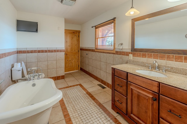 bathroom featuring tile patterned floors, a bathing tub, vanity, and tile walls