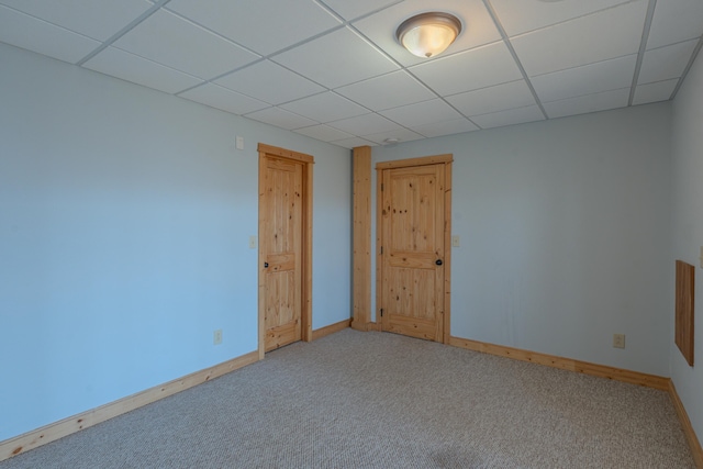 unfurnished room featuring a drop ceiling, carpet floors, and baseboards