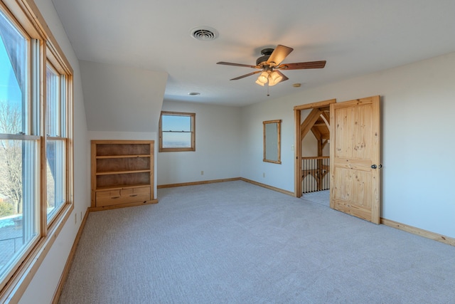 spare room featuring light colored carpet, a ceiling fan, and baseboards