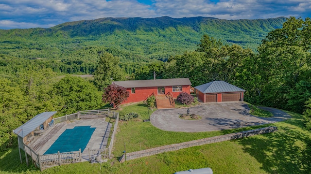 aerial view of property and surrounding area featuring a forest and a mountain backdrop