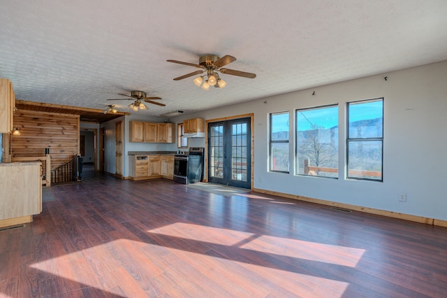 unfurnished living room featuring wooden walls, dark hardwood / wood-style floors, a textured ceiling, and french doors