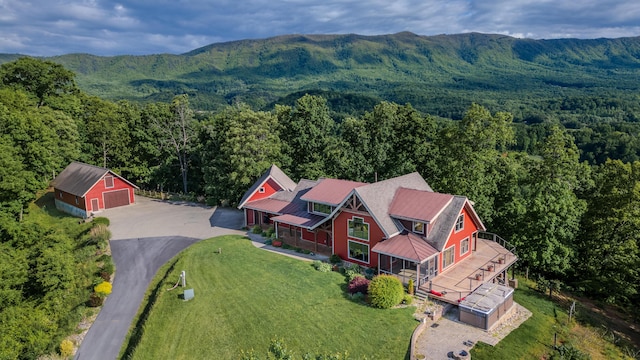 aerial view of property and surrounding area featuring a forest and a mountainous background