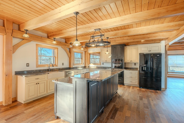 kitchen featuring a kitchen island, decorative light fixtures, sink, dark stone counters, and black appliances