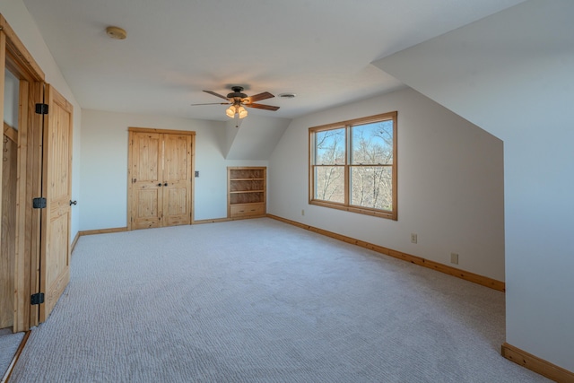 additional living space with vaulted ceiling, light colored carpet, and ceiling fan