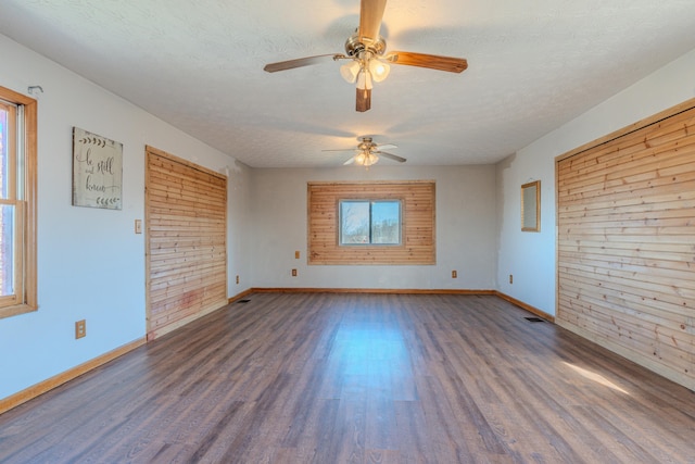 spare room featuring dark wood-type flooring, ceiling fan, and a textured ceiling