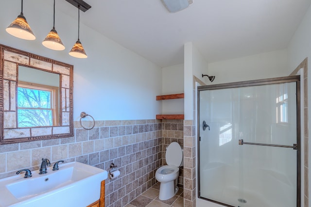 bathroom with toilet, a shower with shower door, tile walls, vanity, and tile patterned flooring