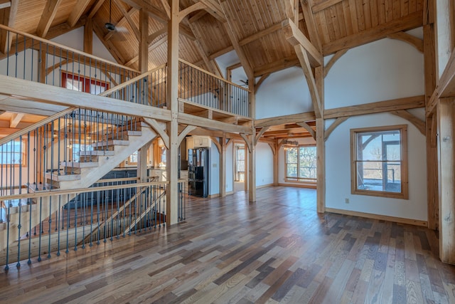 unfurnished living room featuring high vaulted ceiling, wood finished floors, baseboards, beam ceiling, and wooden ceiling
