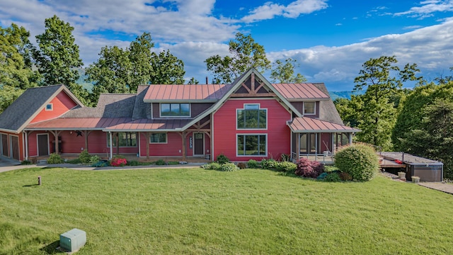 view of front of house with a standing seam roof, a front yard, metal roof, an attached garage, and a porch