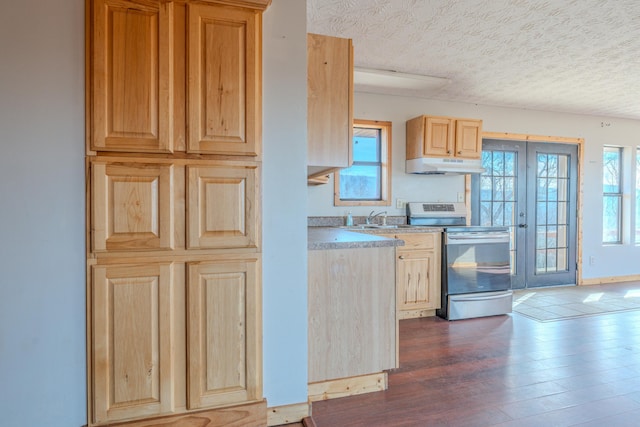 kitchen with electric stove, under cabinet range hood, dark wood-type flooring, a textured ceiling, and healthy amount of natural light