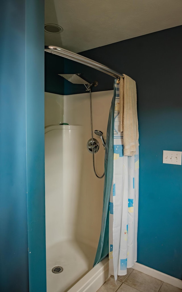 full bath with a shower stall, tile patterned floors, and baseboards