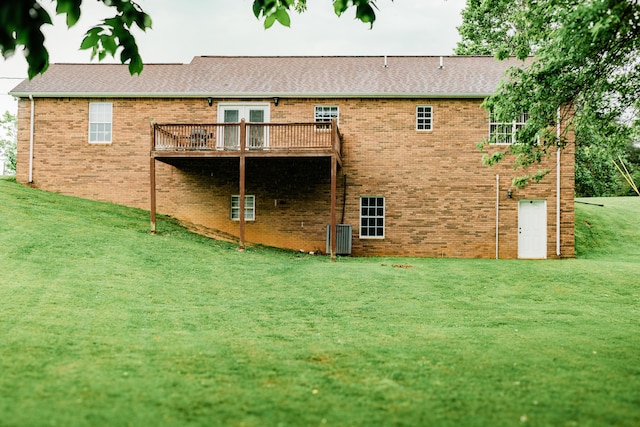 back of house featuring a wooden deck, a yard, brick siding, a shingled roof, and cooling unit