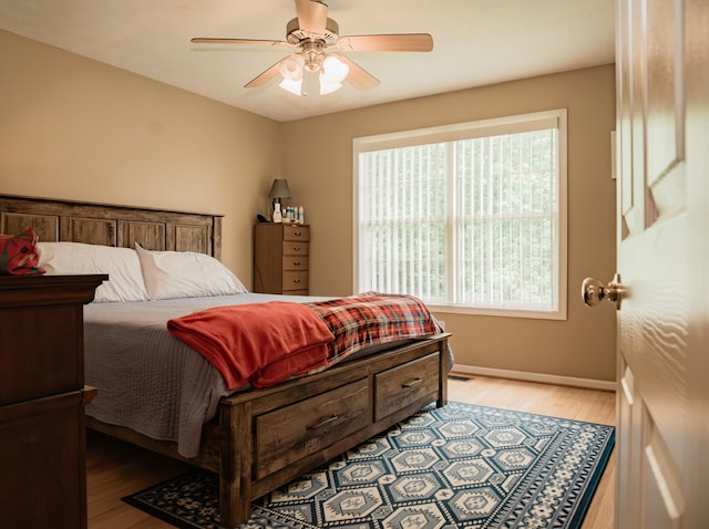 bedroom with light wood finished floors, baseboards, and a ceiling fan