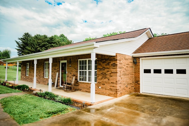 ranch-style home featuring a porch, an attached garage, brick siding, and driveway