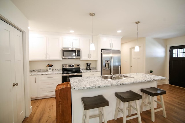 1161 Wooddale Rd, Morristown, TN 37814 - kitchen featuring stainless steel appliances, a sink, light wood finished floors, white cabinetry, and a kitchen island with sink
