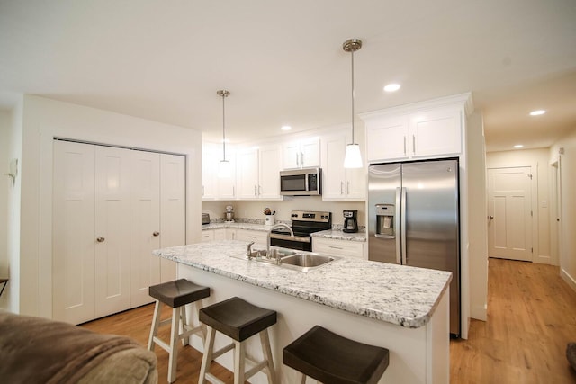 1161 Wooddale Rd, Morristown, TN 37814 - kitchen featuring stainless steel appliances, light wood-type flooring, white cabinets, a kitchen bar, and recessed lighting