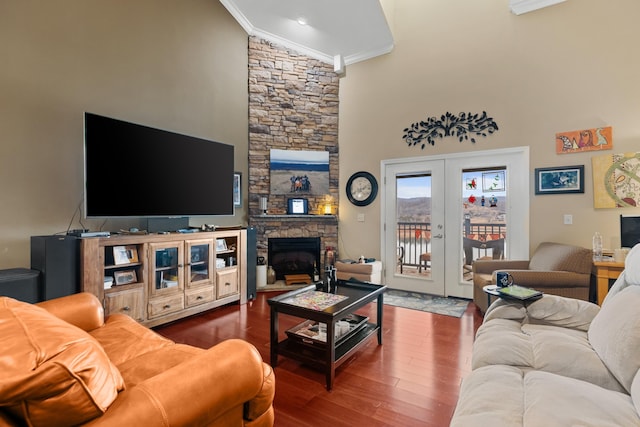 living room with hardwood / wood-style flooring, a high ceiling, a fireplace, ornamental molding, and french doors