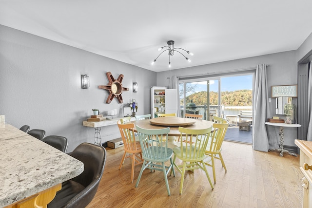 dining area with light hardwood / wood-style flooring and a notable chandelier