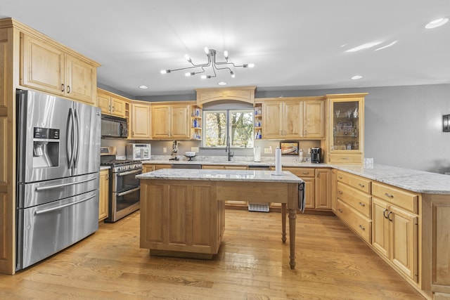 kitchen featuring light stone countertops, appliances with stainless steel finishes, light wood-type flooring, and a center island