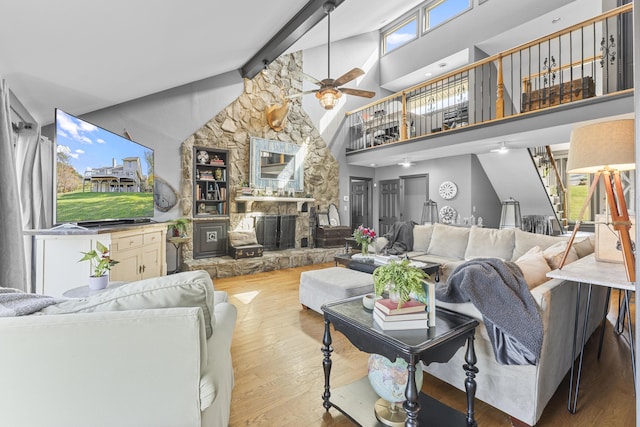 living room featuring high vaulted ceiling, a stone fireplace, ceiling fan, beam ceiling, and wood-type flooring