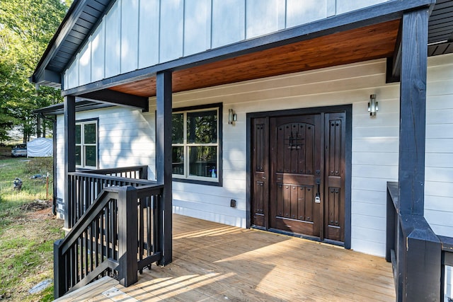 entrance to property featuring a porch and a wooden deck