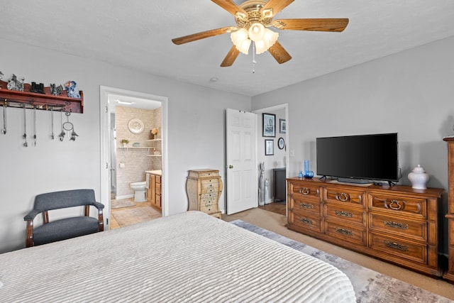 carpeted bedroom with ensuite bath and ceiling fan