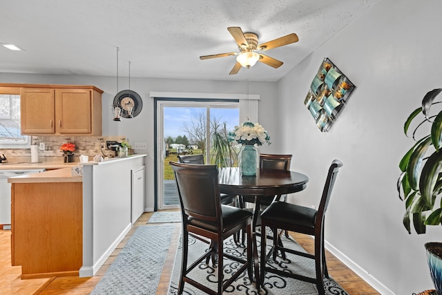 dining area with light wood-type flooring, a textured ceiling, and ceiling fan