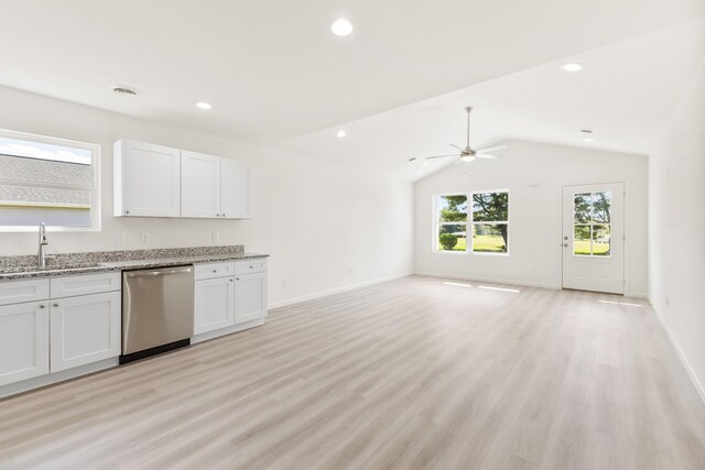 kitchen with open floor plan, stainless steel dishwasher, a sink, light stone counters, and white cabinets