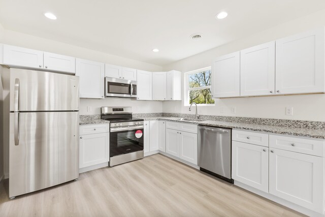kitchen featuring white cabinets, stainless steel appliances, and light wood finished floors