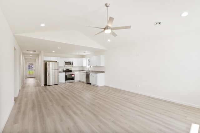 unfurnished living room featuring baseboards, ceiling fan, a sink, and light wood-style floors