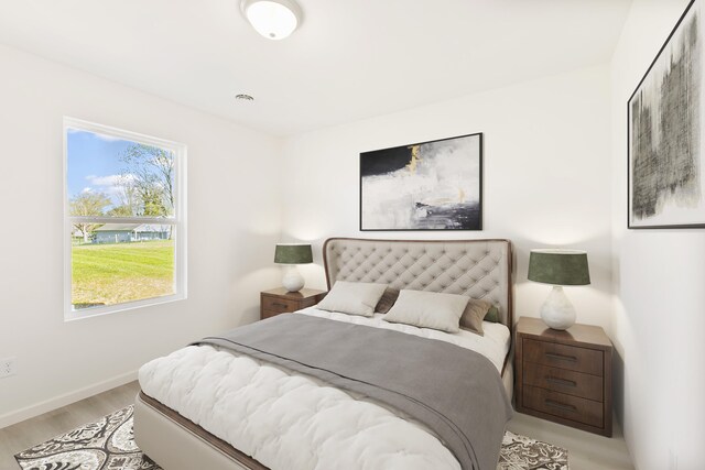 bedroom featuring a tray ceiling, multiple windows, and light wood finished floors