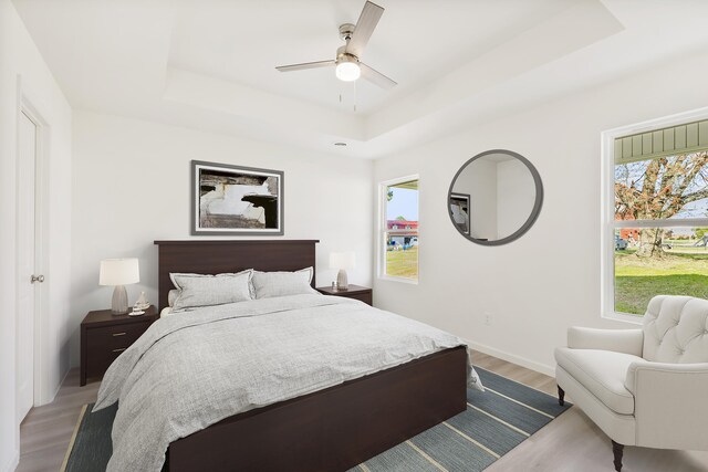 empty room featuring baseboards, a tray ceiling, and light wood finished floors