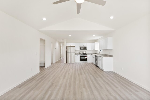 kitchen with white cabinetry, lofted ceiling, stainless steel appliances, baseboards, and light wood-style flooring