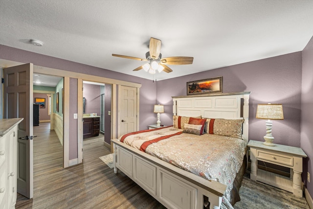 bedroom featuring ceiling fan, dark hardwood / wood-style flooring, and ensuite bath