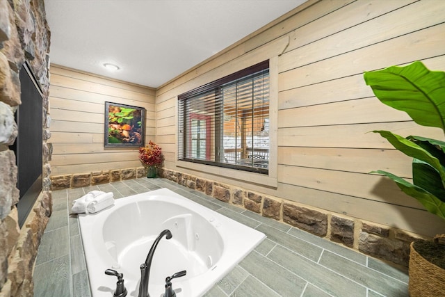 bathroom featuring wooden walls and a relaxing tiled tub