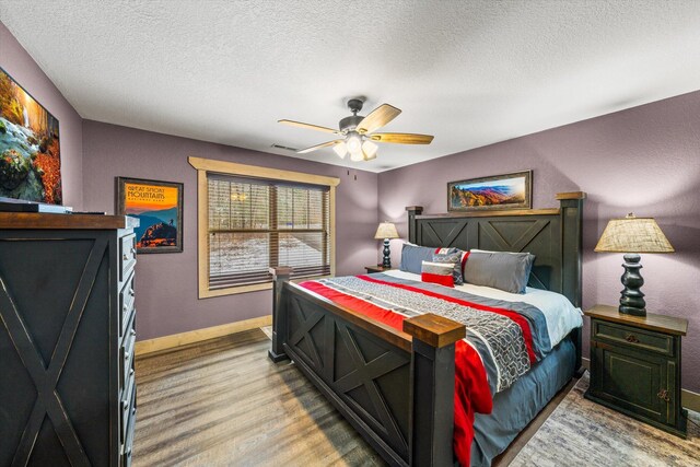 bedroom with a textured ceiling, hardwood / wood-style flooring, and ceiling fan