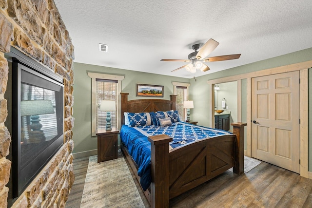 bedroom with ceiling fan, wood-type flooring, and a textured ceiling