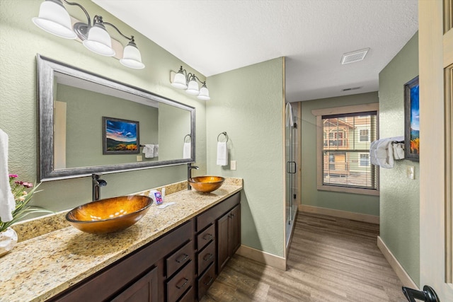 bathroom featuring vanity, wood-type flooring, a textured ceiling, and an enclosed shower