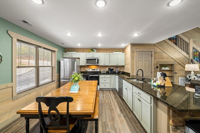 kitchen with built in shelves, stainless steel appliances, wood walls, and wood-type flooring