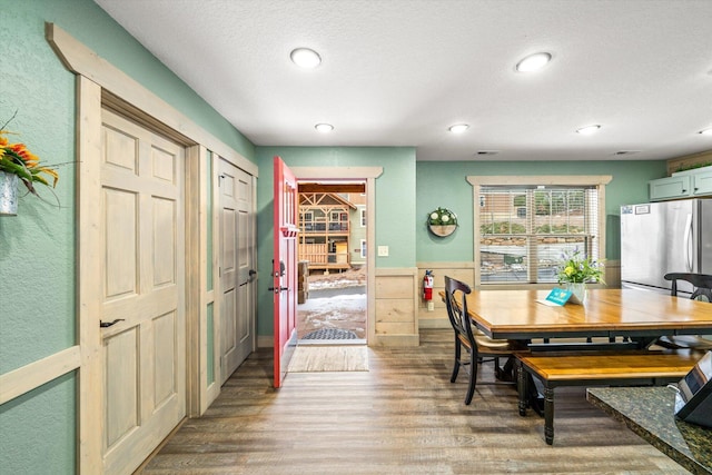 dining space featuring a textured ceiling, hardwood / wood-style flooring, and wooden walls